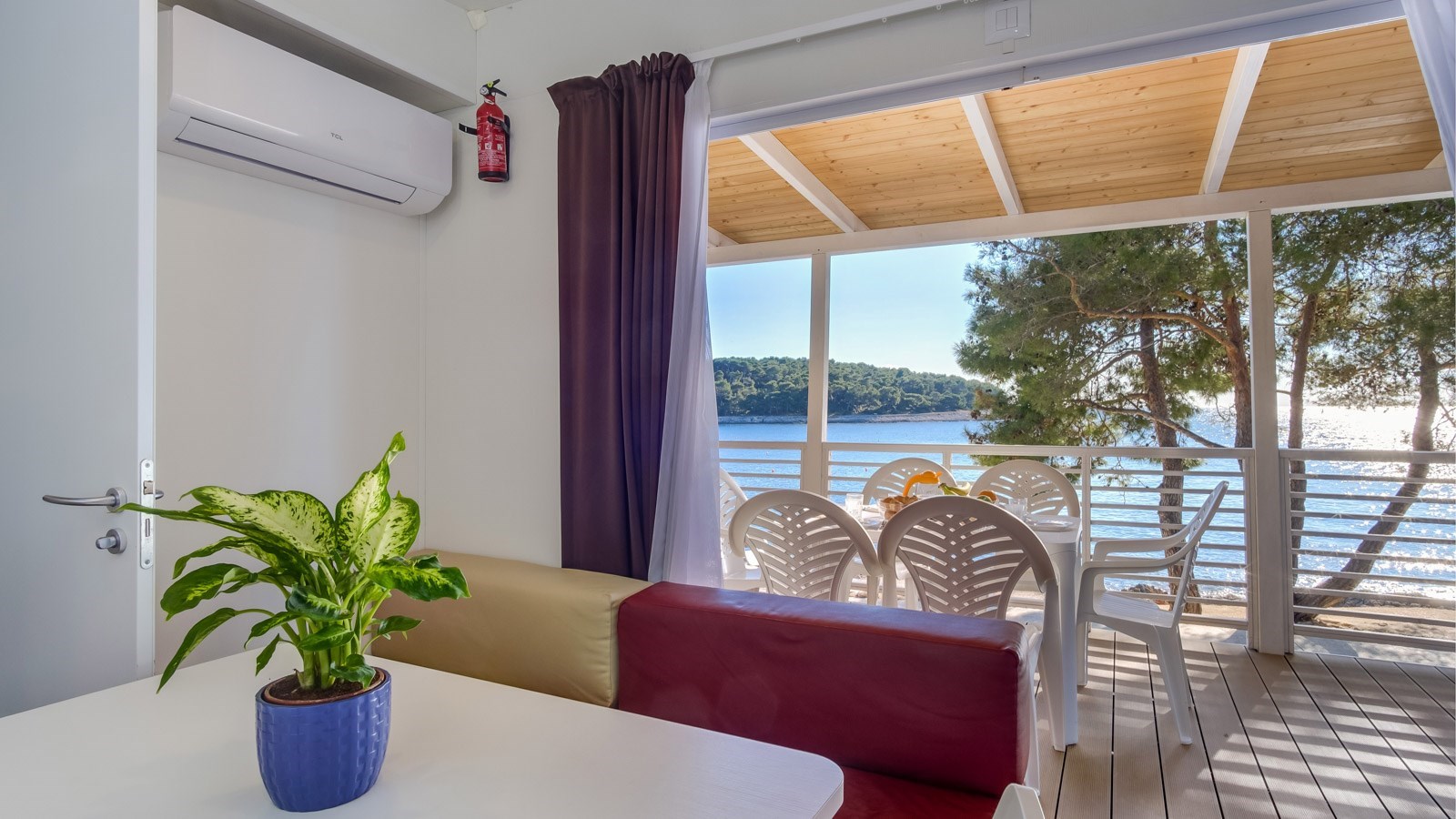 Notranjost sobe z rastlino na mizi in pogledom na morje skozi balkon