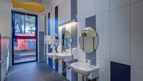 Modern bathroom with three sinks and circular mirrors
