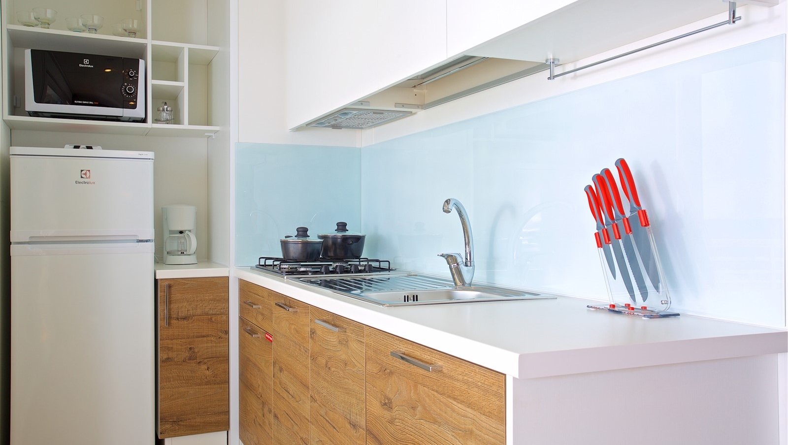 Modern kitchen complete with fridge, microwave, pots, pans, dishes and cutlery